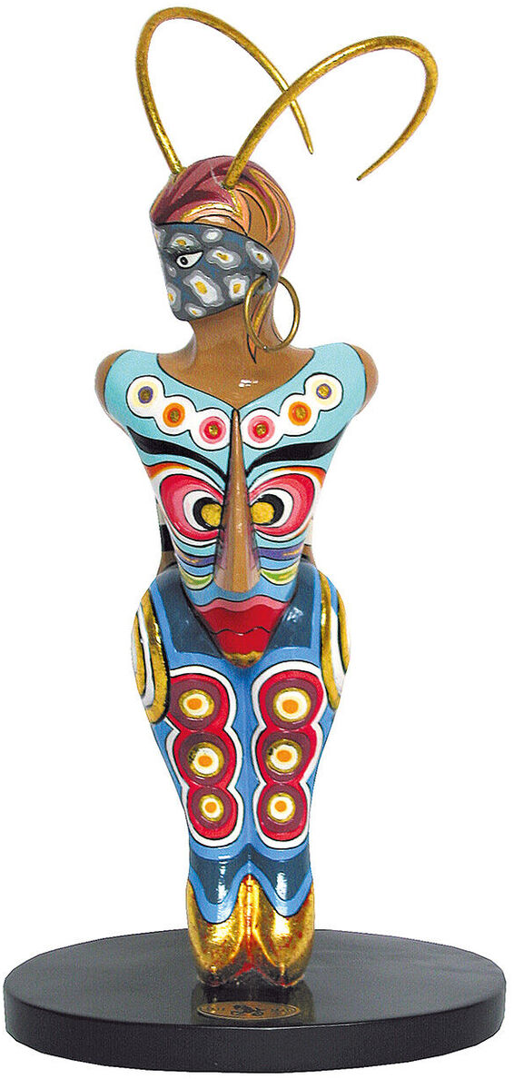 Eine kunstvolle Skulptur von Thomas Hoffmann (Tom's Drag), die ein Sternzeichen darstellt. Die Figur ist farbenfroh mit dominanten Blau-, Rot- und Goldtönen. Sie steht auf einem schwarzen Sockel.