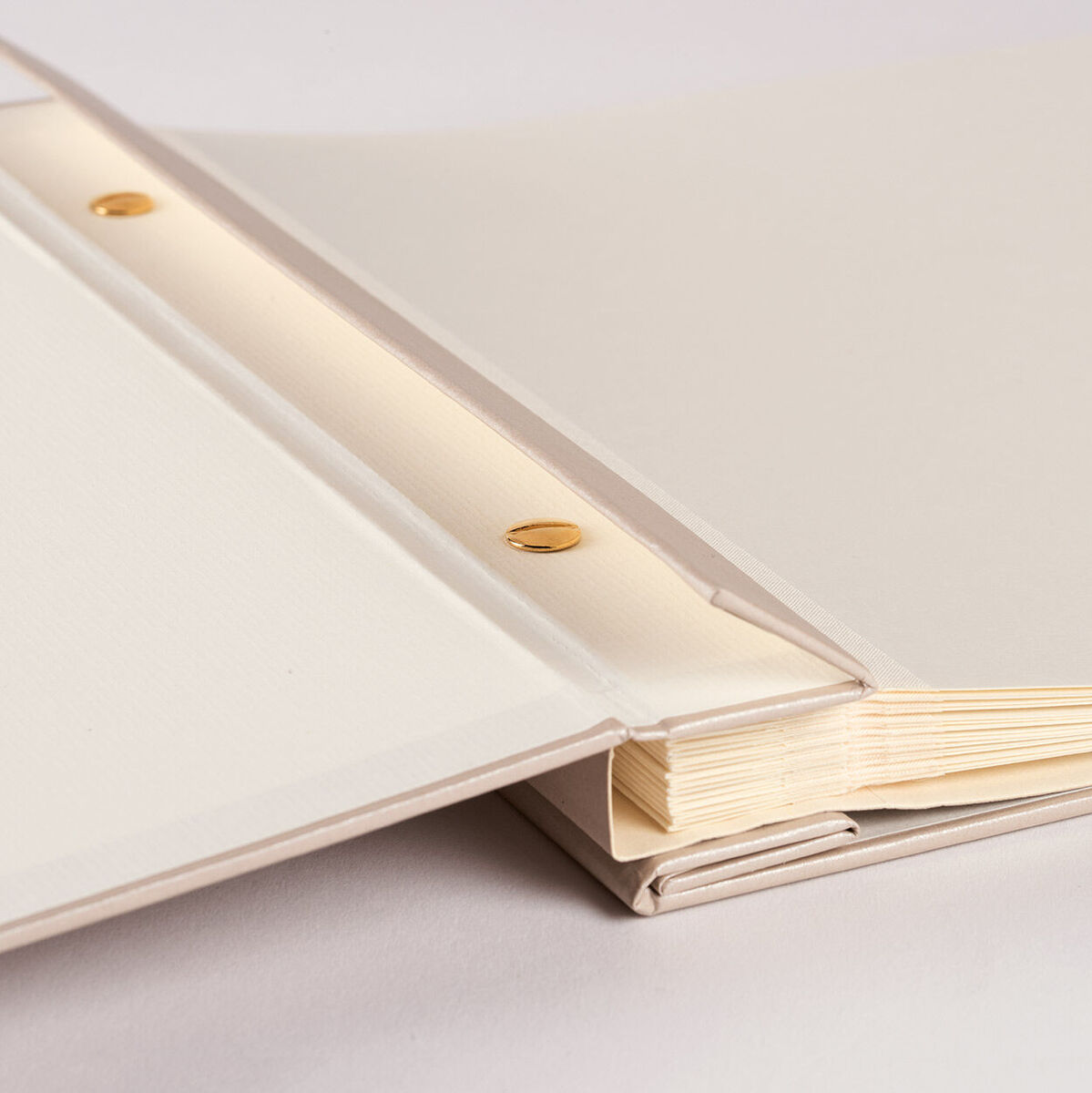 Ein Fotoalbum mit weißen und beige-farbenen Seiten sowie goldenen Befestigungsschrauben, perfekt zum Aufbewahren von wertvollen Erinnerungen.