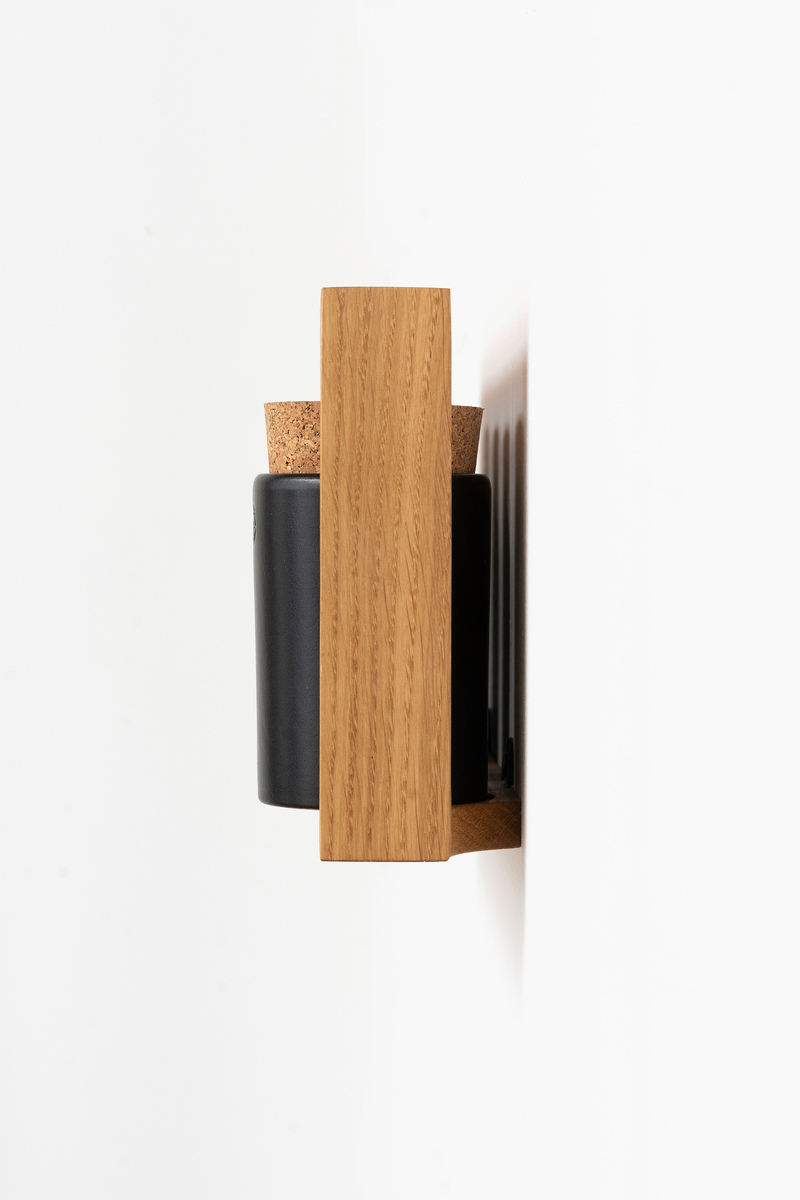 Ein Gewürzregal der Marke »bocuse«, das an einer weißen Wand befestigt ist. Das Regal besteht aus hellem Holz und beherbergt schwarze Gewürzbehälter mit Korkverschlüssen.