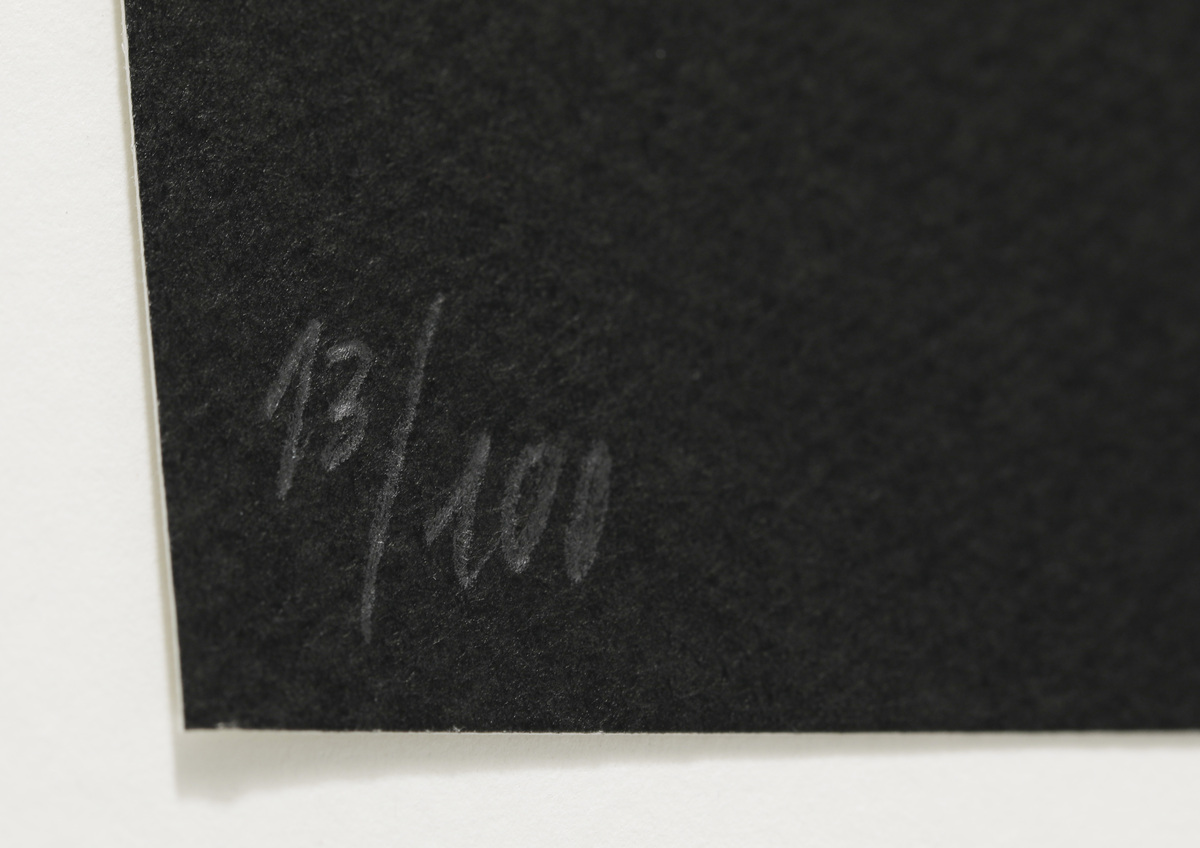 Eine Nahaufnahme einer Kunstwerk-Signatur auf einem schwarz-weißen Kunstdruck mit der Editionnummer 13/100.