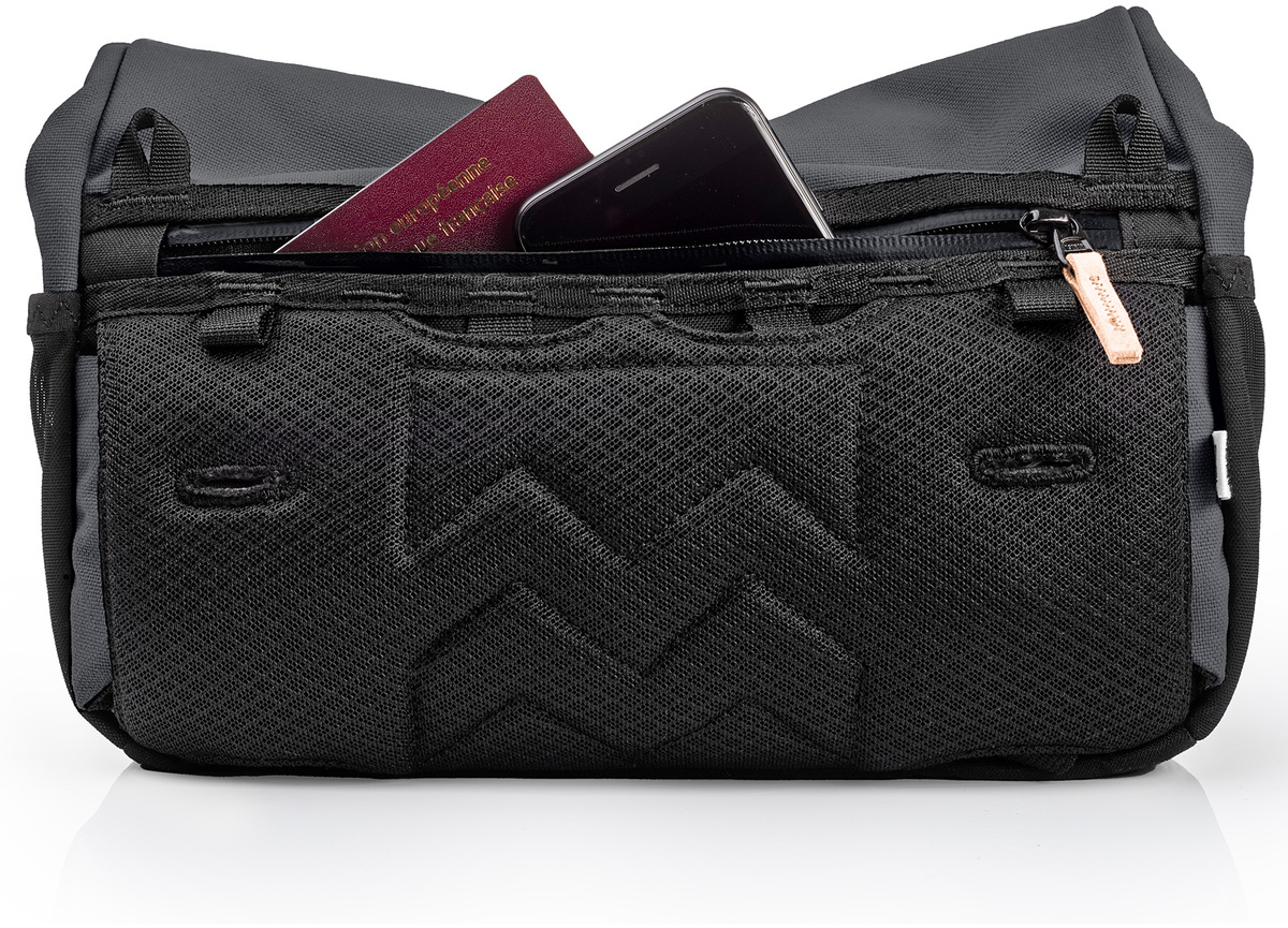 Eine schwarze Umhängetasche namens »Piha« mit mehreren Reißverschlussfächern, in denen man einen Reisepass und ein Smartphone sehen kann. Die Tasche hat ein strapazierfähiges, minimalistisches Design und ist für den täglichen Gebrauch sowie für Reisen geeignet.