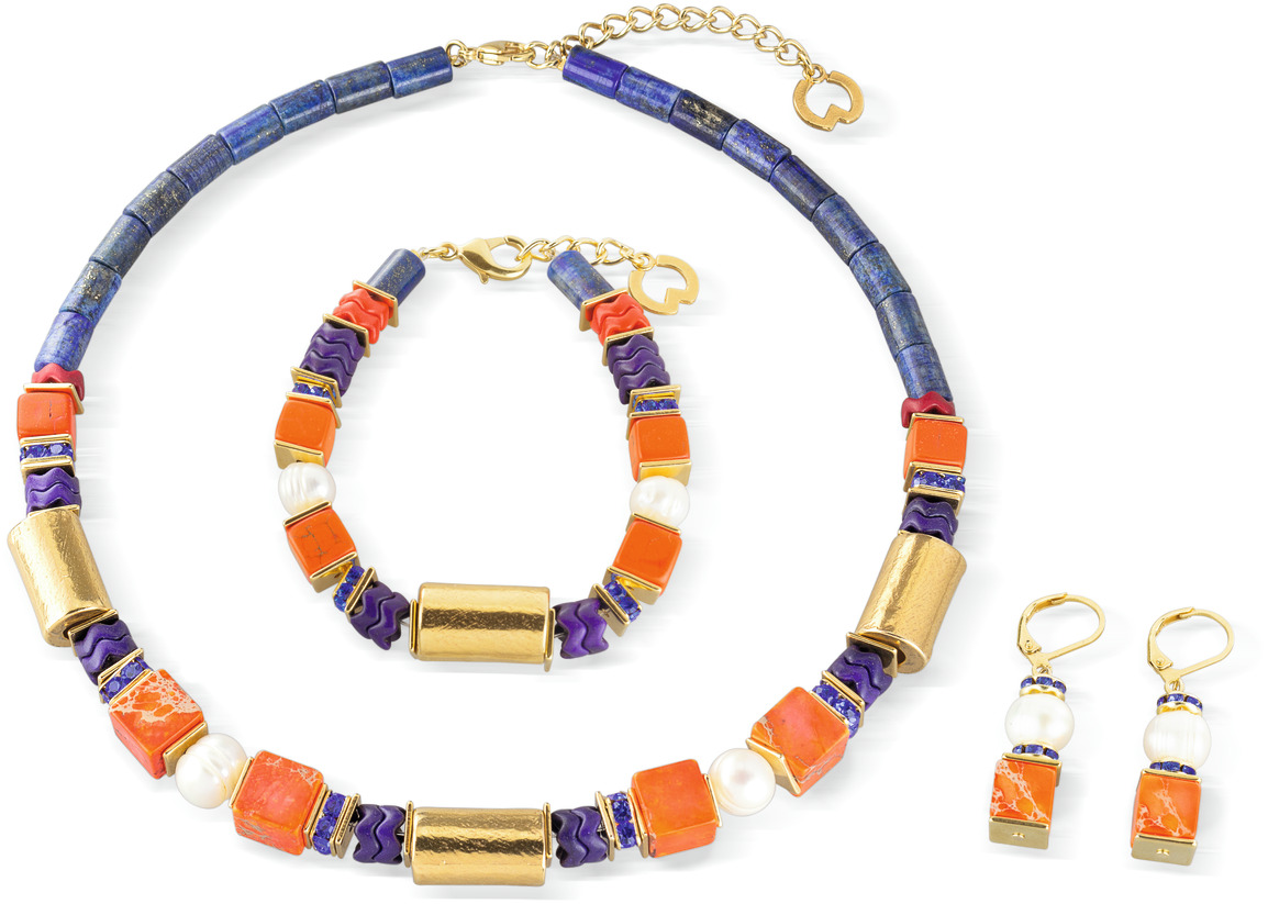 Ein elegantes Schmuckset von Petra Waszak mit dem Namen 'Soleil Levant', bestehend aus einer Halskette, einem Armband und einem Paar Ohrringe. Die Teile sind in Blau-, Rot- und Goldtönen gehalten und verziert mit Perlen.