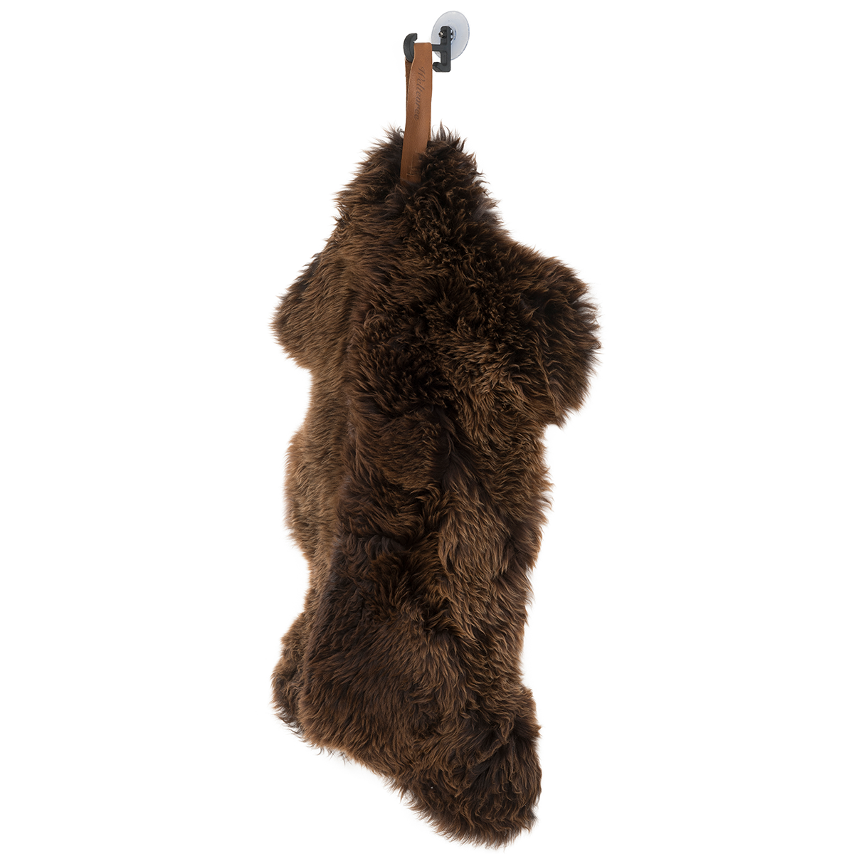 Ein braunes Schafsfell mit einer Lederschlaufe hängt an einem Haken vor weißem Hintergrund. Das Fell wirkt weich, flauschig und naturbelassen. Perfekt als Dekoration oder gemütliches Wohnaccessoire.