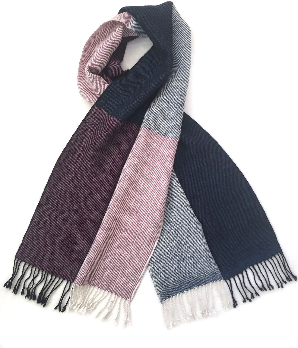 Ein eleganter Alpakaschal mit quadratischem Muster in Blau, Weiß, Rosa, Grau und Bordeaux. Der Schal ist weich und wollartig, mit Fransen an den Enden.