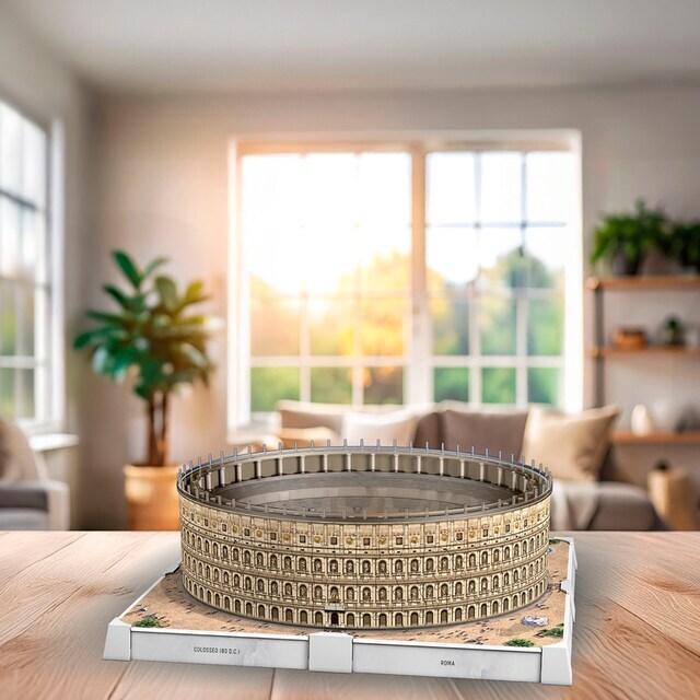 Detailgetreues 3D-Puzzle des Kolosseums von Ravensburger steht leuchtend auf einem Holztisch in einem hellen, stilvollen Wohnzimmer mit großen Fenstern und Zimmerpflanzen. Das fertige Modell ist präzise gestaltet und wird von Tageslicht inszeniert.