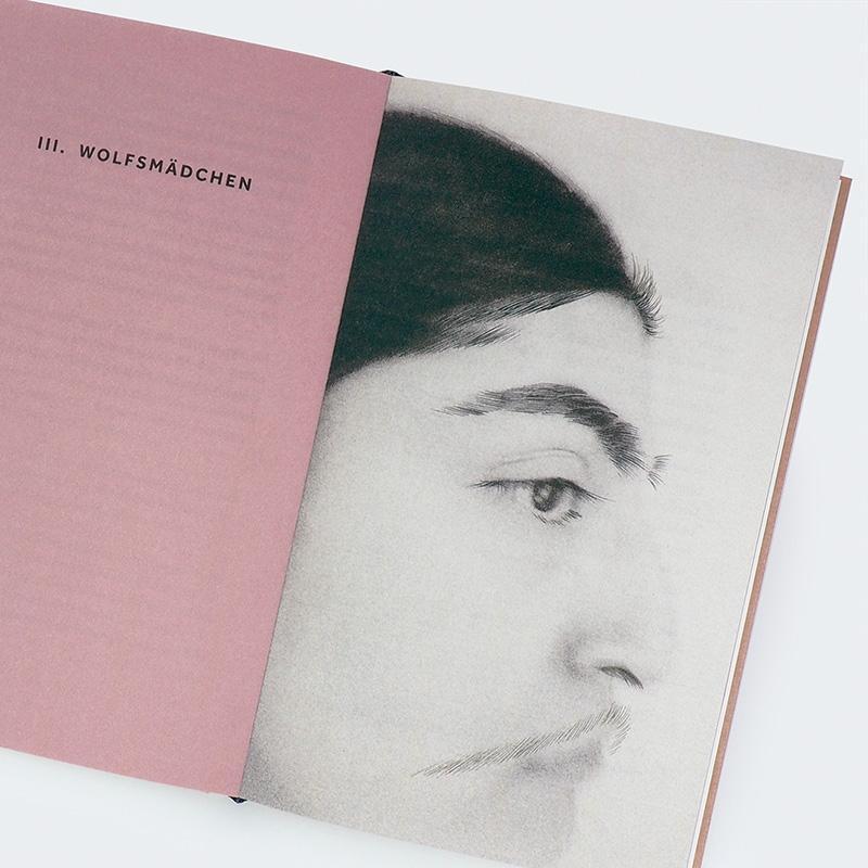 Eine Buchseite mit einem schwarzen und weißen Profilbild eines Gesichts und dem Titel 'III. Wolfsmädchen' auf rosafarbenem Hintergrund.