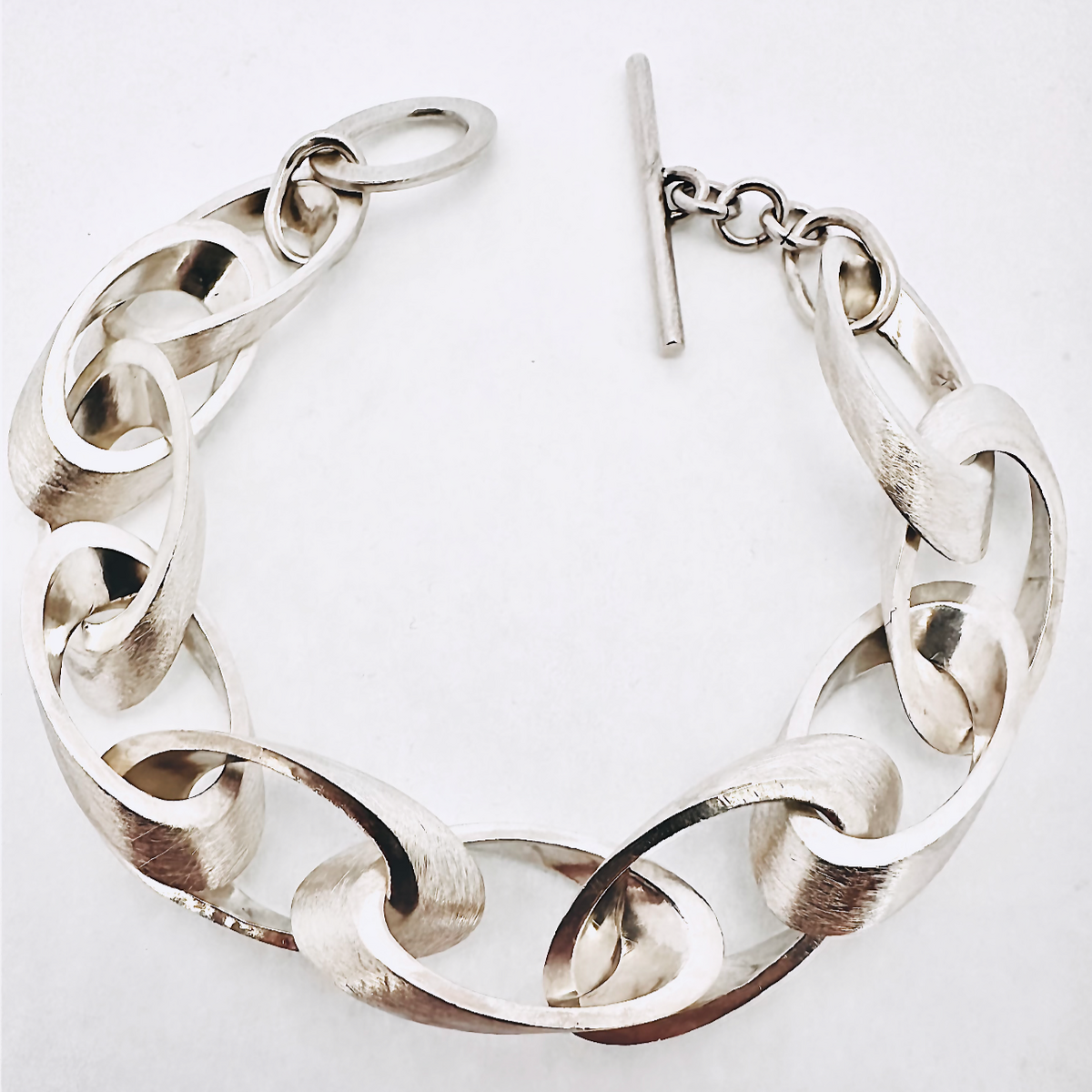 Silbernes Armband im Kettenstil mit Elipsen-Design und einem Verschluss, auf weißem Hintergrund, elegant und modern.