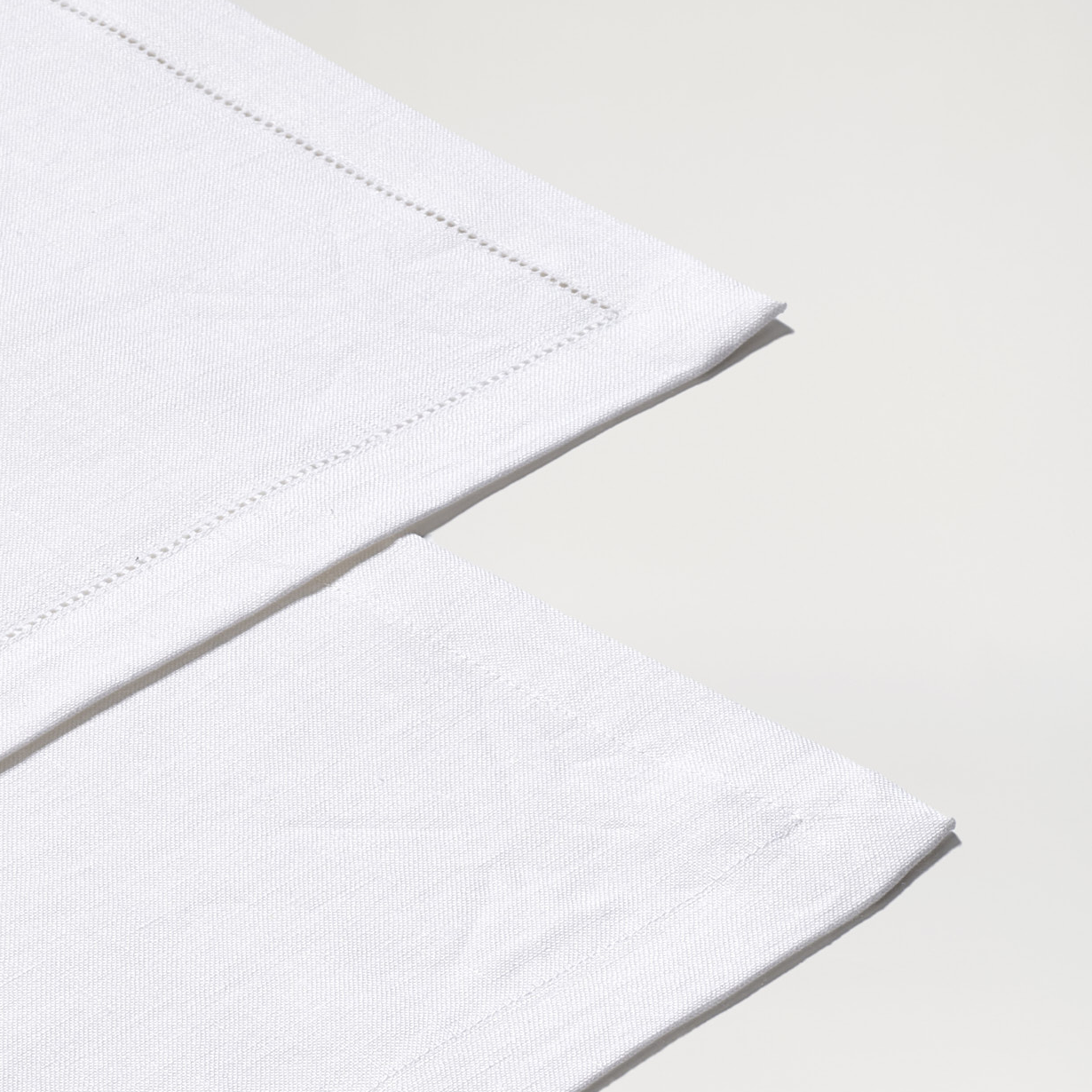 Schlichter, rechteckiger Leinen-Tischläufer in Weiß, auf einem hellen Untergrund ausgebreitet. Die feine Webstruktur und der dezente Saum sind gut sichtbar. Das Produkt wirkt hochwertig und minimalistisch, ideal als elegante Tischdekoration für festliche Anlässe, Familienfeiern oder den täglichen Gebrauch.