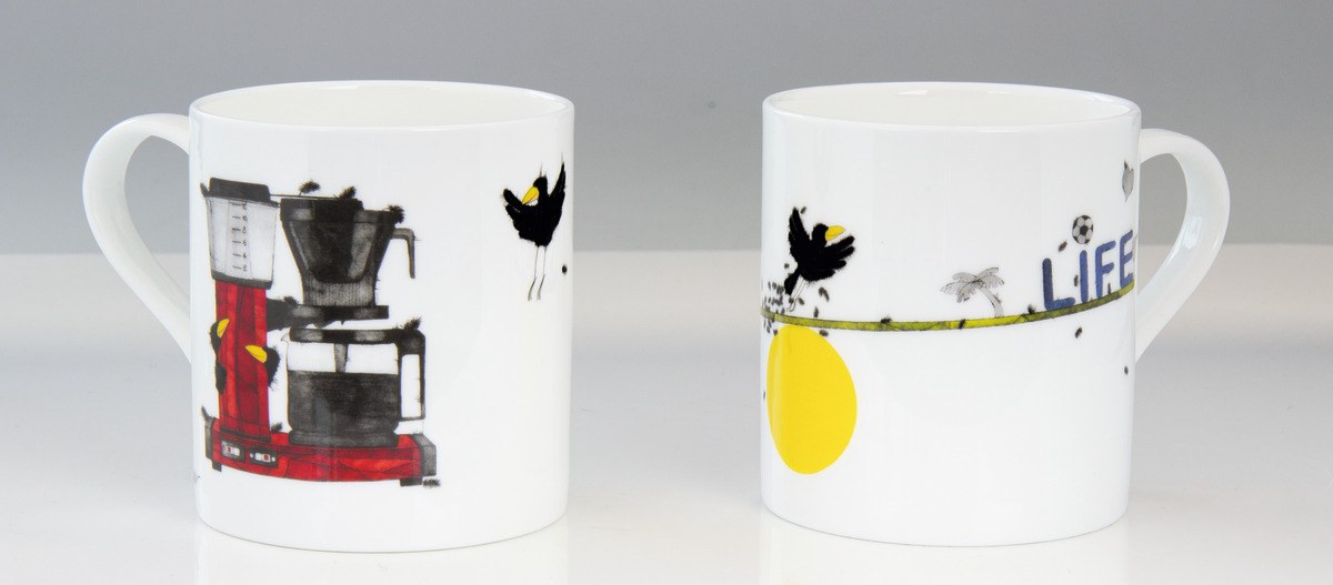 Set aus zwei weißen Kaffeebechern mit Aufdrucken. Einer zeigt eine rote Kaffeemaschine und Vögel, der andere „Life“-Schriftzug, Vögel und eine gelbe Sonne.