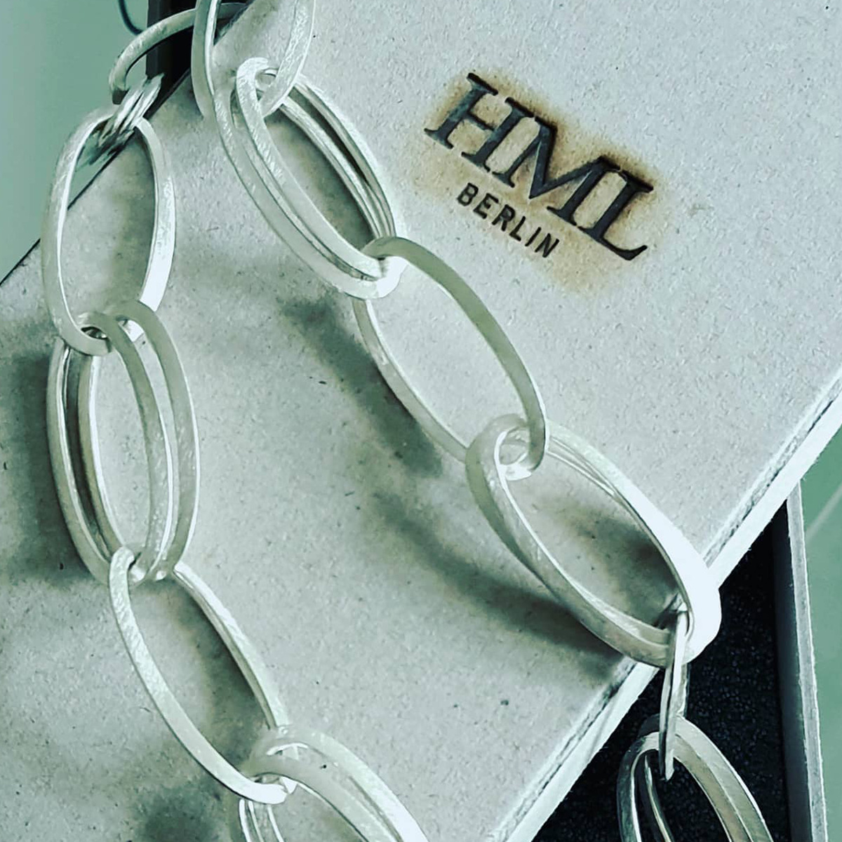Detailaufnahme des handgefertigten Colliers »GRACE« aus 925er Silber von HML Berlin. Die Schmuckkette mit großen, ovalen Gliedern liegt auf einer edlen, hellgrauen Schmuckschachtel mit dem Aufdruck 'HML BERLIN'. Zeitloses, puristisches Design, hochwertig verarbeitet.