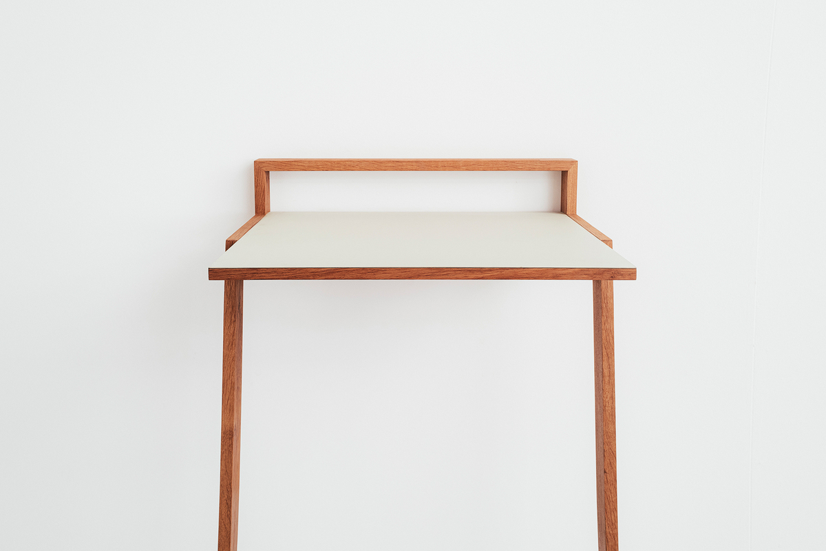 Ein minimalistisches und modernes Stehpult, genannt »buckowski«, hauptsächlich aus Holz gefertigt. Es hat eine weiße Arbeitsfläche und braune Beine und Struktur. Das Design ist schlicht und elegant, ideal für Büros oder Home Office.