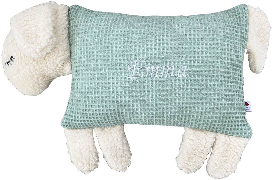 Ein Kuscheltierkissen in Form eines Schafs mit weißem Plüsch und hellgrünem Stoff mit dem Namen Emma darauf.