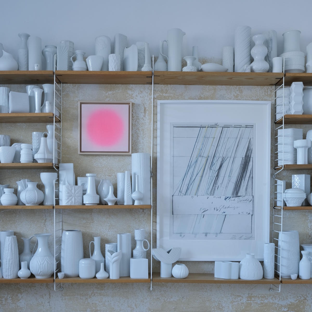 Zu sehen ist ein Kunstwerk der ZEIT-Sonderedition »Sorbet«, Apricot von Studio Anastasia Benko. Das Unikat im Apricot-Ton ist gerahmt und hängt an einer Wand mit weißen Vasen und Gefäßen auf offenen Holzregalen. Im Hintergrund strukturierte, beigefarbene Wand.