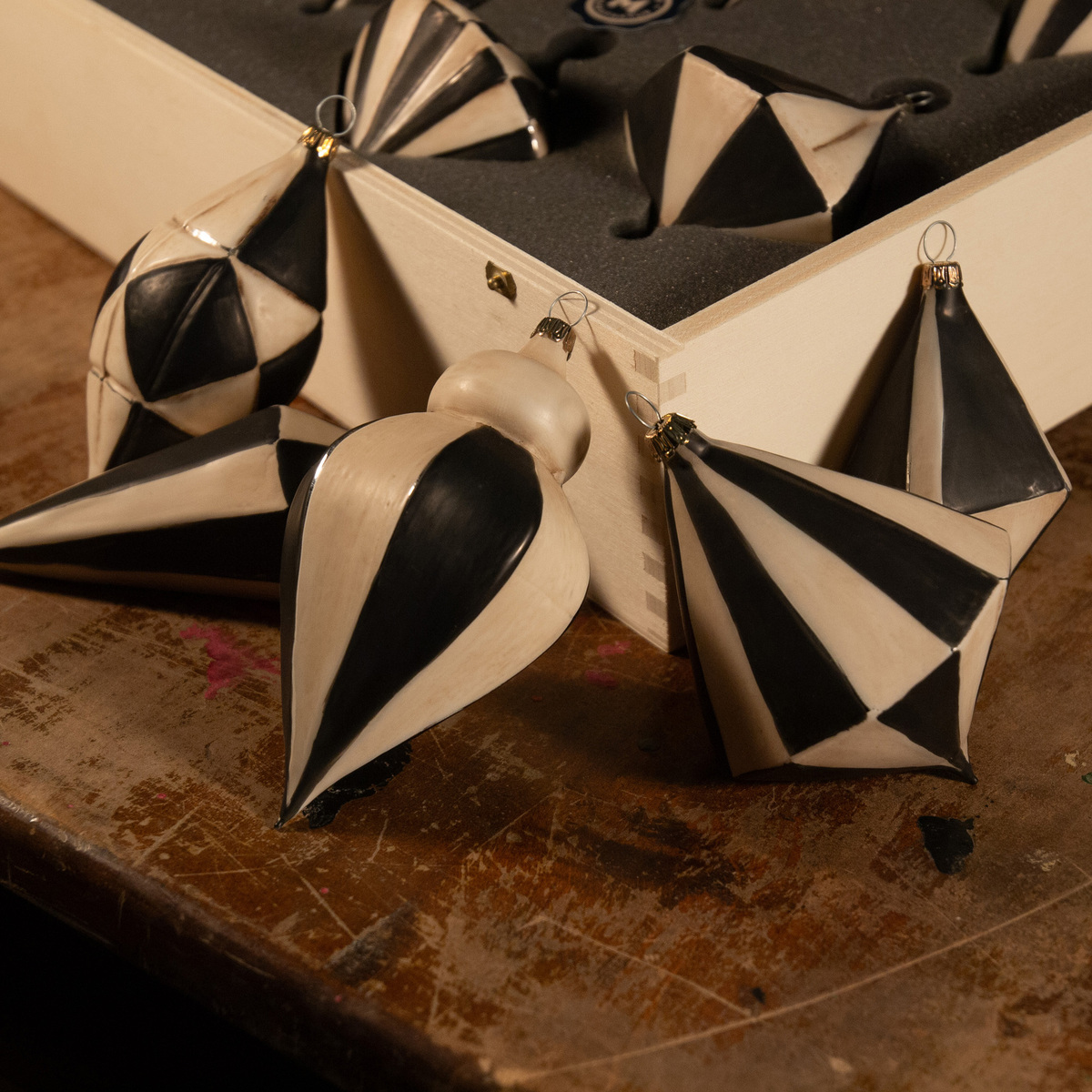 Ein Set von zehn Christbaumkugeln in Schwarz-Weiß-Design. Die Kugeln befinden sich in einer Holzkiste und sind kunstvoll gestaltet. Perfekt als Weihnachtsdekoration für den Weihnachtsbaum.