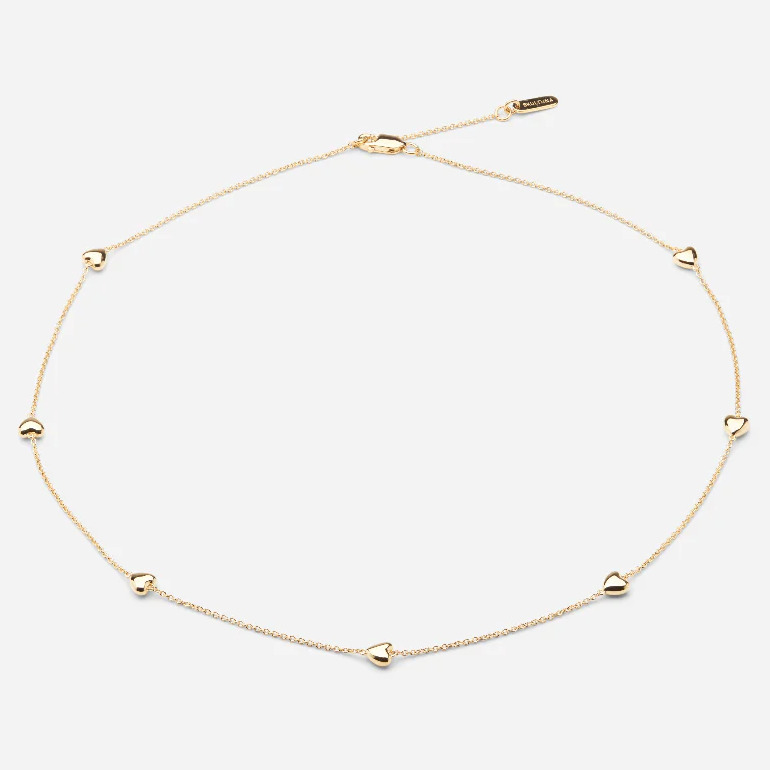 Filigranes Collier aus vergoldetem 925er Sterlingsilber mit sieben kleinen, einzeln platzierten Herzanhängern entlang einer feinen, goldfarbenen Kette. Die Kette besitzt einen dezenten Glanz und einen verstellbaren Verschluss. Das Design wirkt zart, hochwertig und elegant.