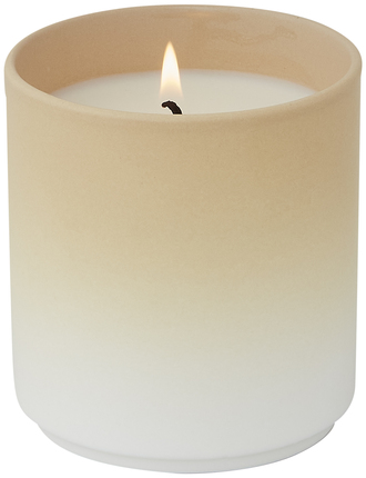Eine Duftkerze mit dem Namen 'DIP DYE' in einem einfachen und eleganten Design. Die Kerze hat eine beige bis cremefarbene Oberfläche und brennt mit einer ruhigen Flamme.