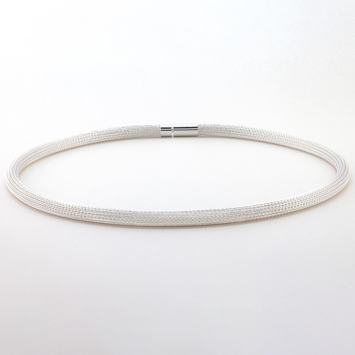 Das Bild zeigt das Collier »Milanaise« von Menard aus feinsten 925er Silberdrähten. Die handgefertigte Kette besitzt ein edles, rundes Strumpfgeflecht ohne Naht und eine glatte, anschmiegsame Oberfläche. Die Kette liegt leicht gewölbt auf hellem Untergrund.