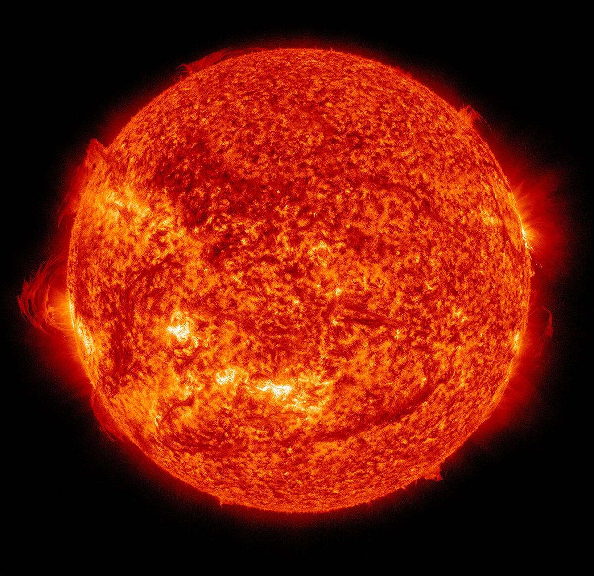 Ein Bild der Sonne, aufgenommen von der NASA's Solar Dynamics Observatory. Die Sonne leuchtet hell in Orange und Rot, wobei ihre Oberfläche durch heiße Plasmaaktivitäten gekennzeichnet ist. Das Bild präsentiert eine detaillierte Ansicht der Sonnenoberfläche gegen einen schwarzen Hintergrund.