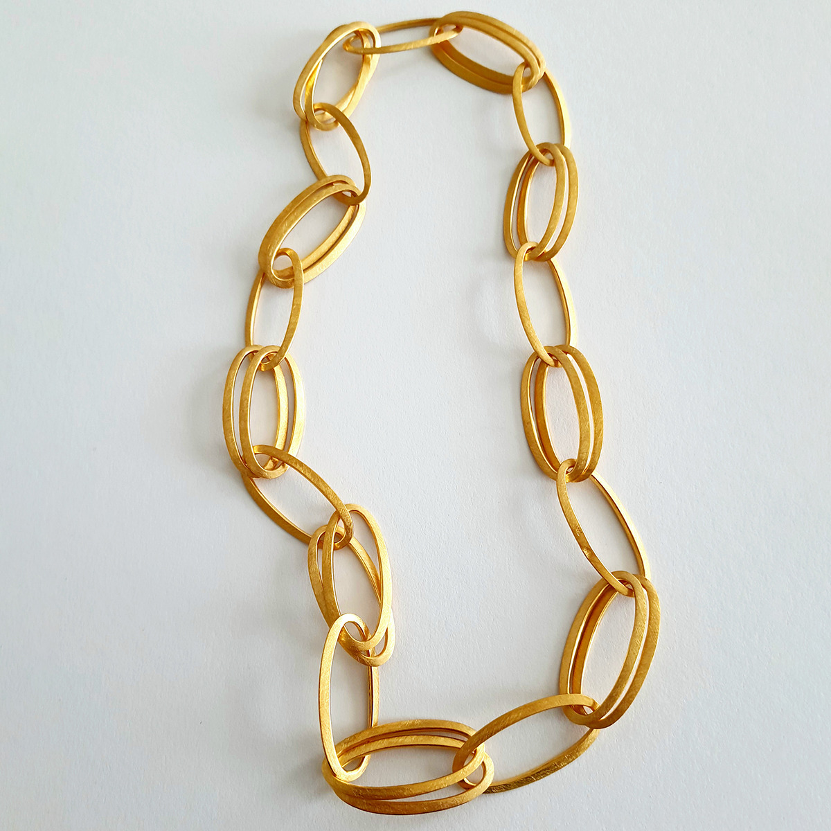 Das Bild zeigt das Collier »GRACE« von HML Berlin, handgefertigt aus 925er Silber und feingoldplattiert. Die Kette besteht aus großen, ovalen, goldfarbenen Gliedern und liegt auf weißem Untergrund. Das Design wirkt edel, modern und puristisch.