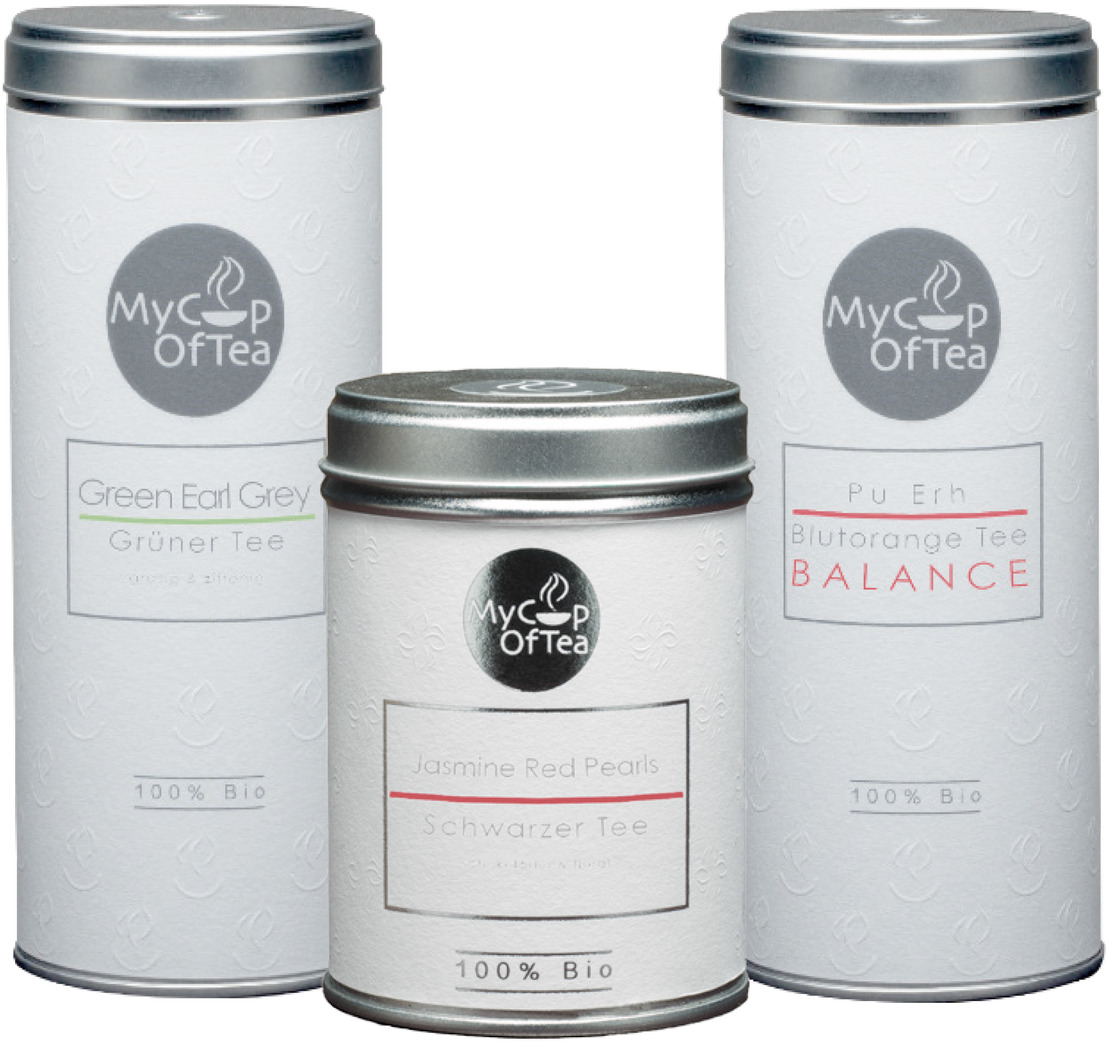 Das Bild zeigt ein Tee-Set »Aroma« mit drei weißen Teedosen. Die Dosen sind mit dem Logo 'My Cup of Tea' versehen. Die Sorten sind Green Earl Grey, Blutorange Tee Pu Erh, und Jasmin Red Pearls. Alle Produkte sind als 100% Bio ausgezeichnet.