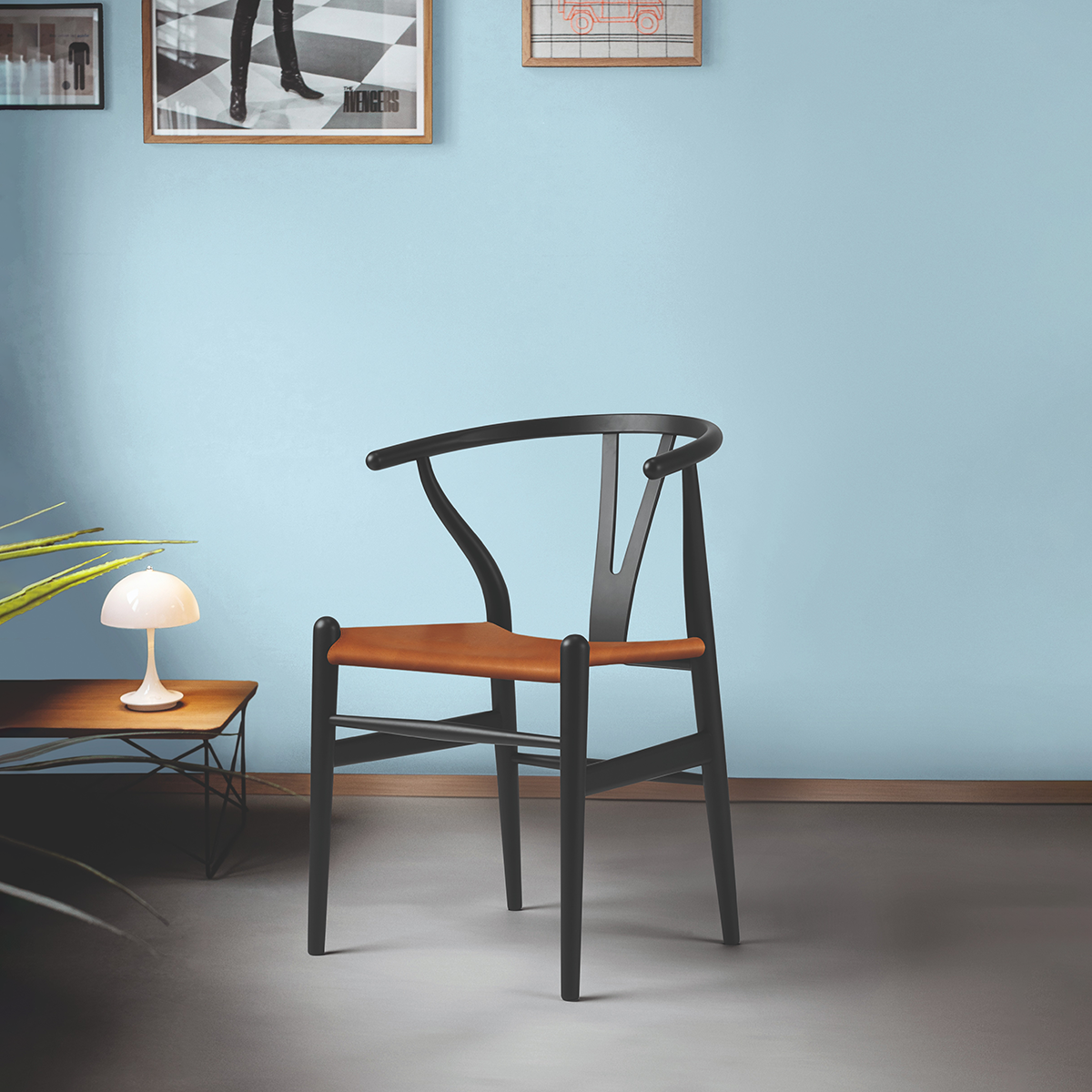 Ein stilvoller Designstuhl aus Buche und Leder, auch bekannt als Wishbone Chair, in einem minimalistisch eingerichteten Raum mit hellblauer Wand, einem niedrigen Tisch mit Tischleuchte und Bodenpflanze.