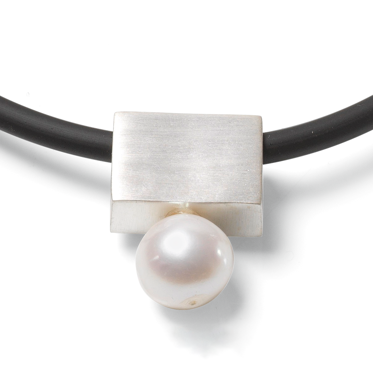 Das Bild zeigt ein elegantes Collier der Marke Ars mundi. Der Anhänger besteht aus einer großen weißen Perle, die von einem rechteckigen, versilberten Messingelement gehalten wird. Das Collier hängt an einem schwarzen Kautschukband. Das Design ist modern und schlicht.
