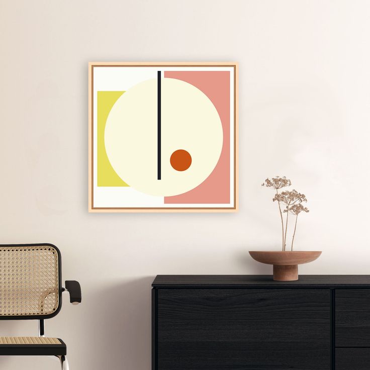 Modernes Leinwandbild mit einem abstrakten, geometrischen Design in Pastellgelb, Weiß, Rosa und Orange, gerahmt an einer hellen Wand über einer schwarzen Kommode dekoriert, mit minimalistischer Einrichtung und getrockneten Blumen.