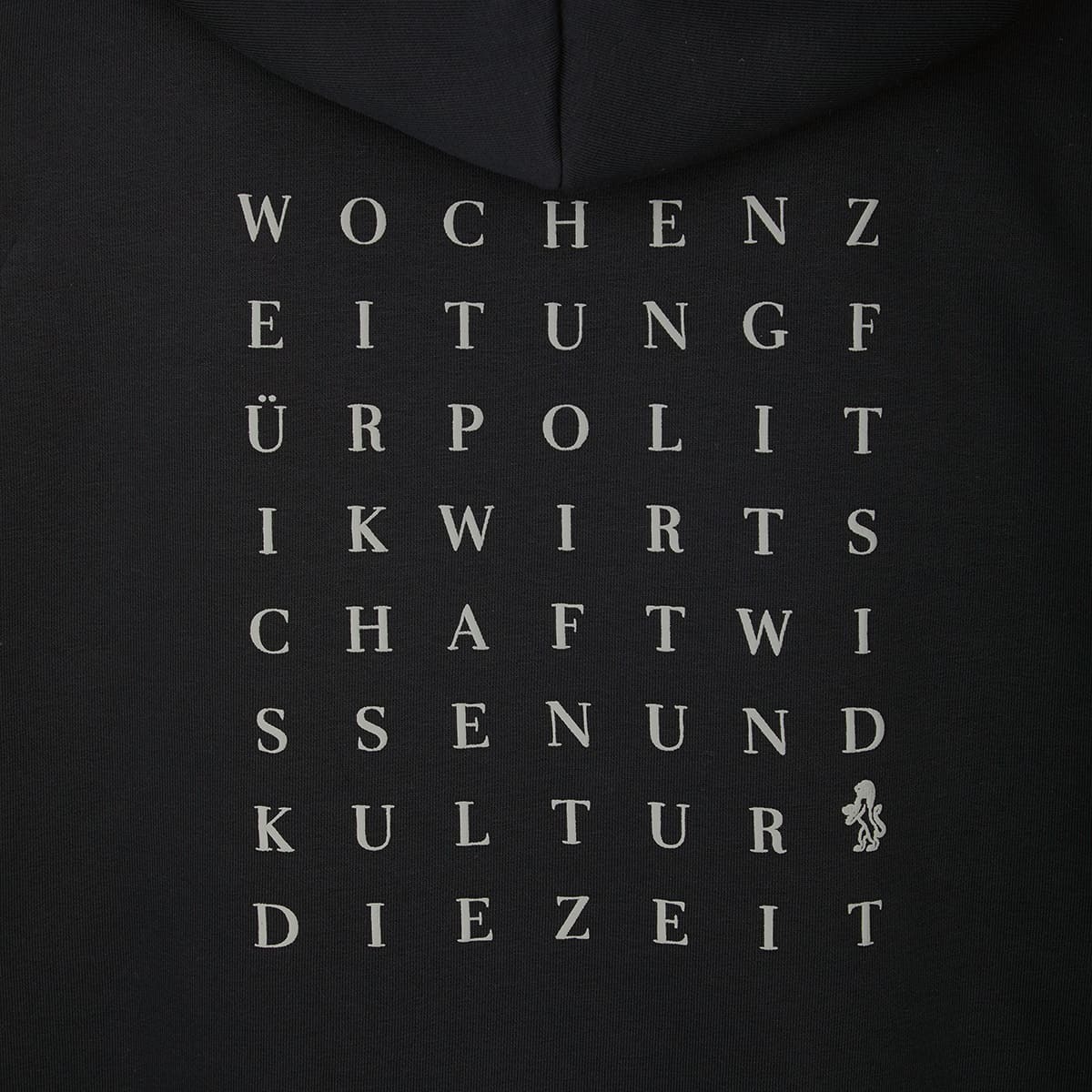 Rückseite eines schwarzen Hoodies aus der ZEIT-Kollektion mit quadratischem, grauem Buchstaben-Print. Die Wörter 'WOCHENZEITUNG', 'POLITIK', 'WIRTSCHAFT', 'WISSEN', 'KULTUR' und 'DIE ZEIT' sind vertikal angeordnet. Unten rechts ein kleines, stilisiertes Engel-Logo.