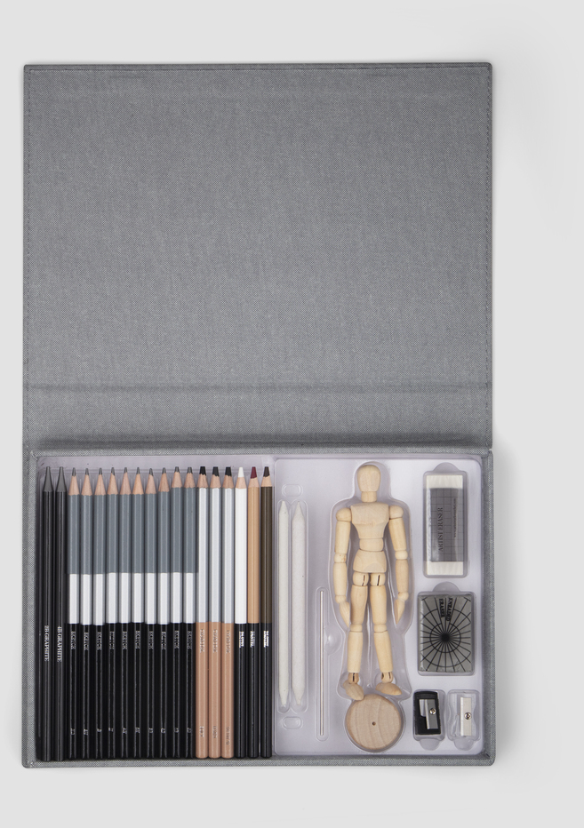 Ein Zeichenset, das Bleistifte, eine Holzmannequins, Radiergummi, Anspitzer und Kohle enthält, präsentiert in einer grauen Schachtel.