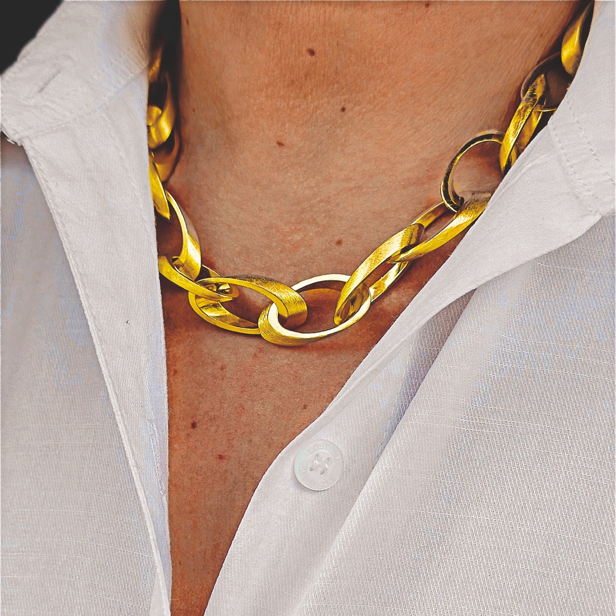 Großgliedriges Collier aus goldfarben feingoldplattiertem 925er Silber liegt auf dem Hals einer Person, die ein weißes Hemd trägt. Die Kette wirkt elegant und edel, hebt sich glänzend vom Stoff ab und betont den Ausschnitt.