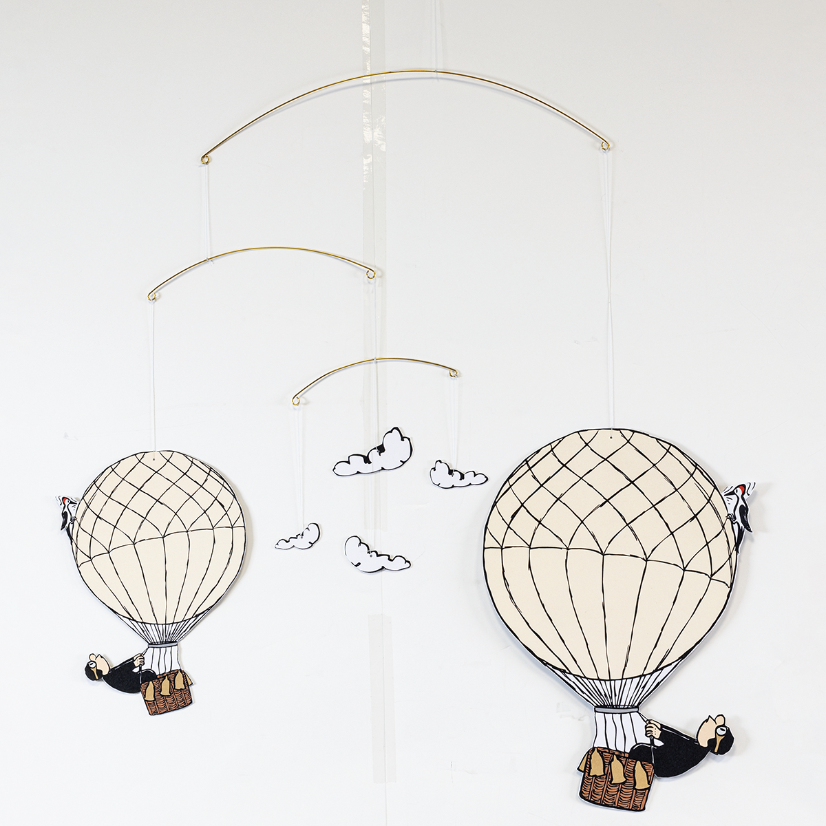 Ein detailreiches Decken-Mobilé von Loriot mit zwei Heißluftballons, jeweils mit Zeichentrick-Figuren im Korb. Drei stilisierte Wolken hängen zwischen den Ballons. Die Motive sind coloriert, die Aufhängung besteht aus feinen goldfarbenen Drahtbögen.