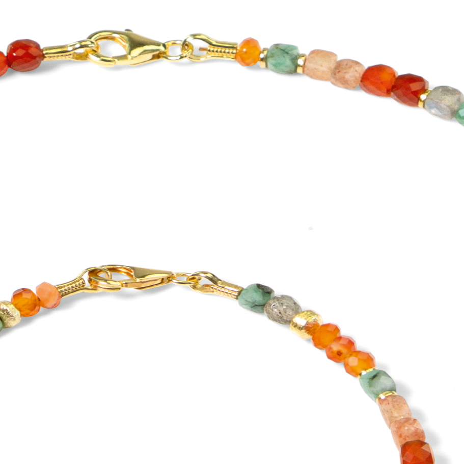 Detailaufnahme zweier Schmuckstücke, bestehend aus feinen, runden Edelsteinperlen in Orange-, Rot-, Grün- und Rosatönen sowie goldfarbenen Verschlüssen. Die Materialien sind 925er Sterlingsilber, Sonnenstein, Karneol, Smaragd und Mondstein.