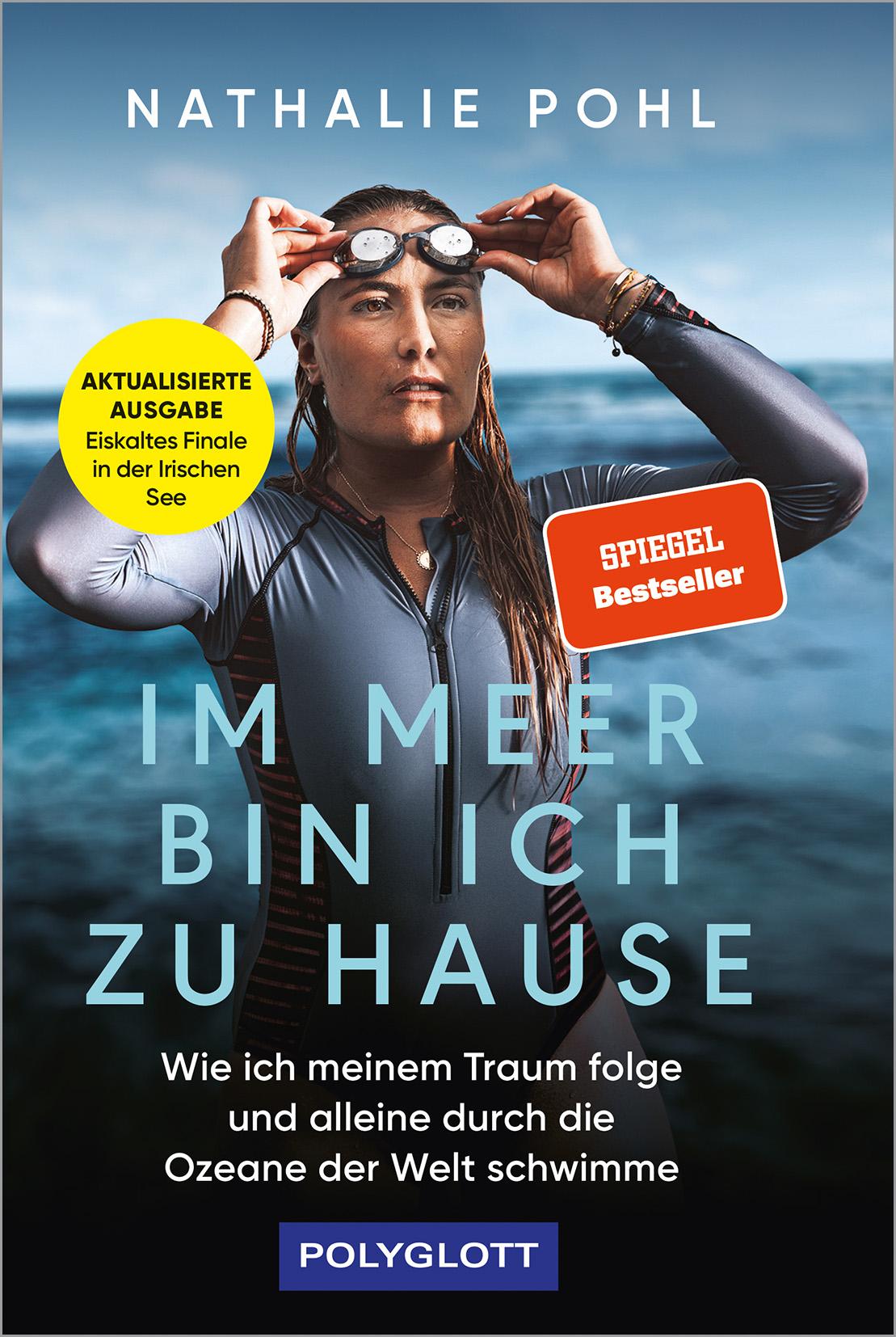 Das Buchcover zeigt Nathalie Pohl, eine Frau in Neoprenanzug und Schwimmbrille am Kopf, die vor einem offenen Meer bei bewölktem Himmel steht. Der Titel 'Im Meer bin ich zu Hause' und der Untertitel stehen im Vordergrund. Die Farben sind hauptsächlich Blau- und Grautöne, unterbrochen von gelben und orangen Akzenten.