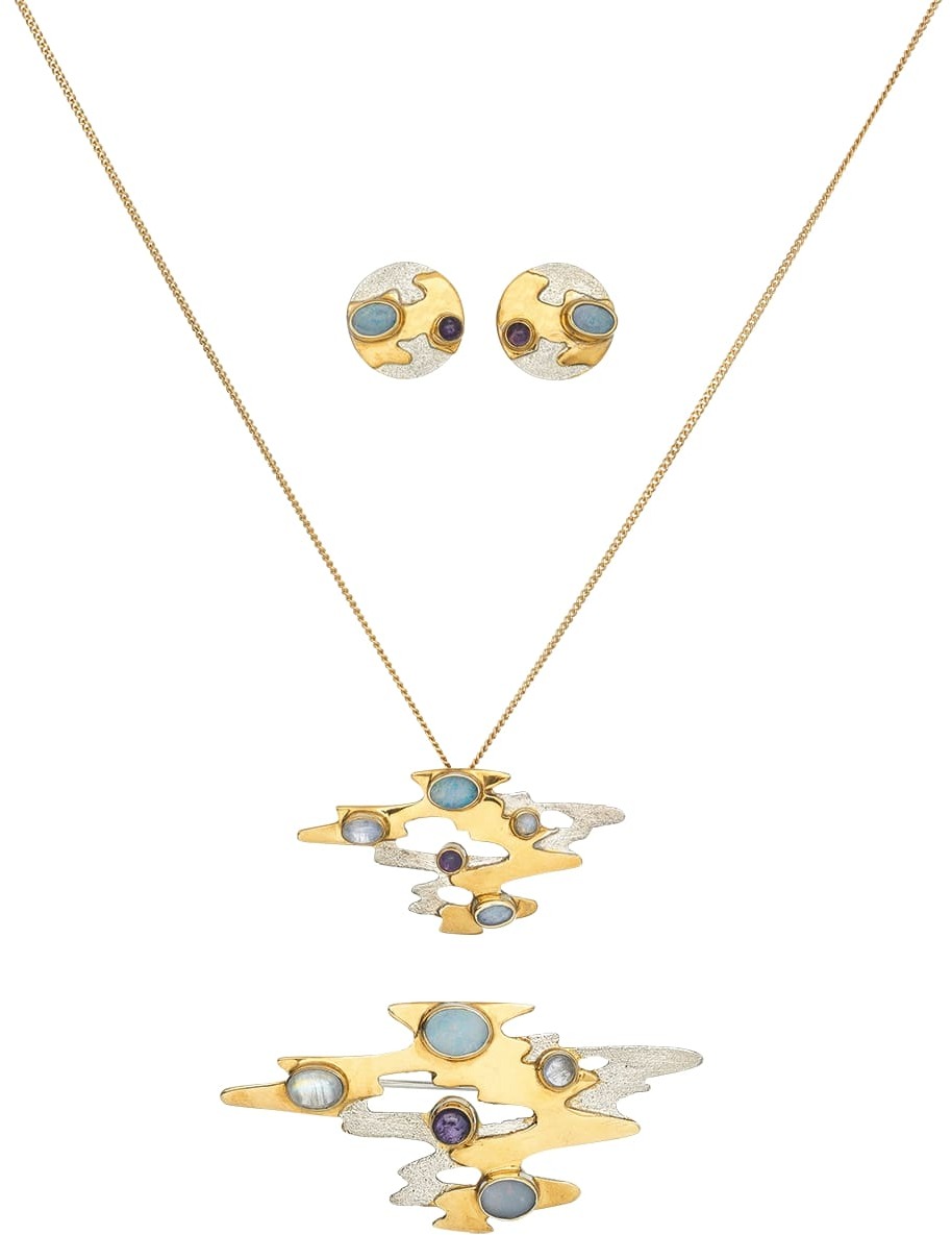 Ein Schmuckset bestehend aus einer Halskette und Ohrringen, inspiriert von Monets Reflektionen. Die Schmuckstücke sind in Gold gehalten und mit blauen, lila und silbernen Details verziert.