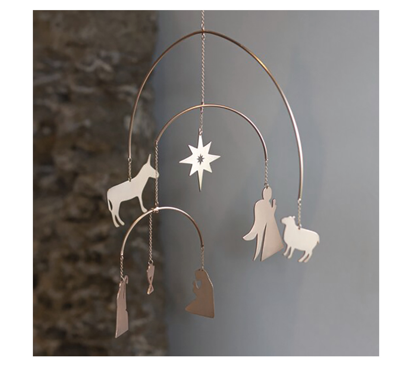 Mobiles Kunstobjekt aus silberfarbenem Metall mit weihnachtlichen Motiven, darunter Engel, Heilige Familie, Schafe, Esel und ein Stern. Das Mobile hängt frei im Raum und eignet sich als minimalistische Weihnachtsdekoration.