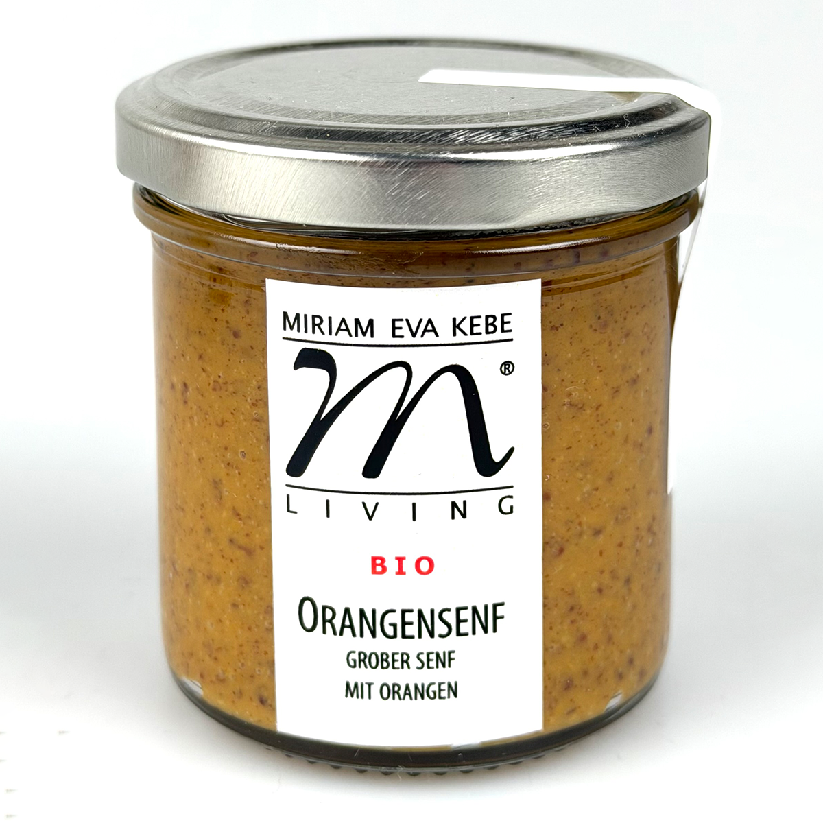 Das Bild zeigt ein rundes Glas mit silbernem Metalldeckel, gefüllt mit orangefarbenem Bio-Orangensenf. Auf dem Glas ist ein weißes Etikett mit schwarzem Schriftzug: 'Miriam Eva Kebe', 'Living', 'BIO', 'Orangensenf grober Senf mit Orangen' zu sehen.