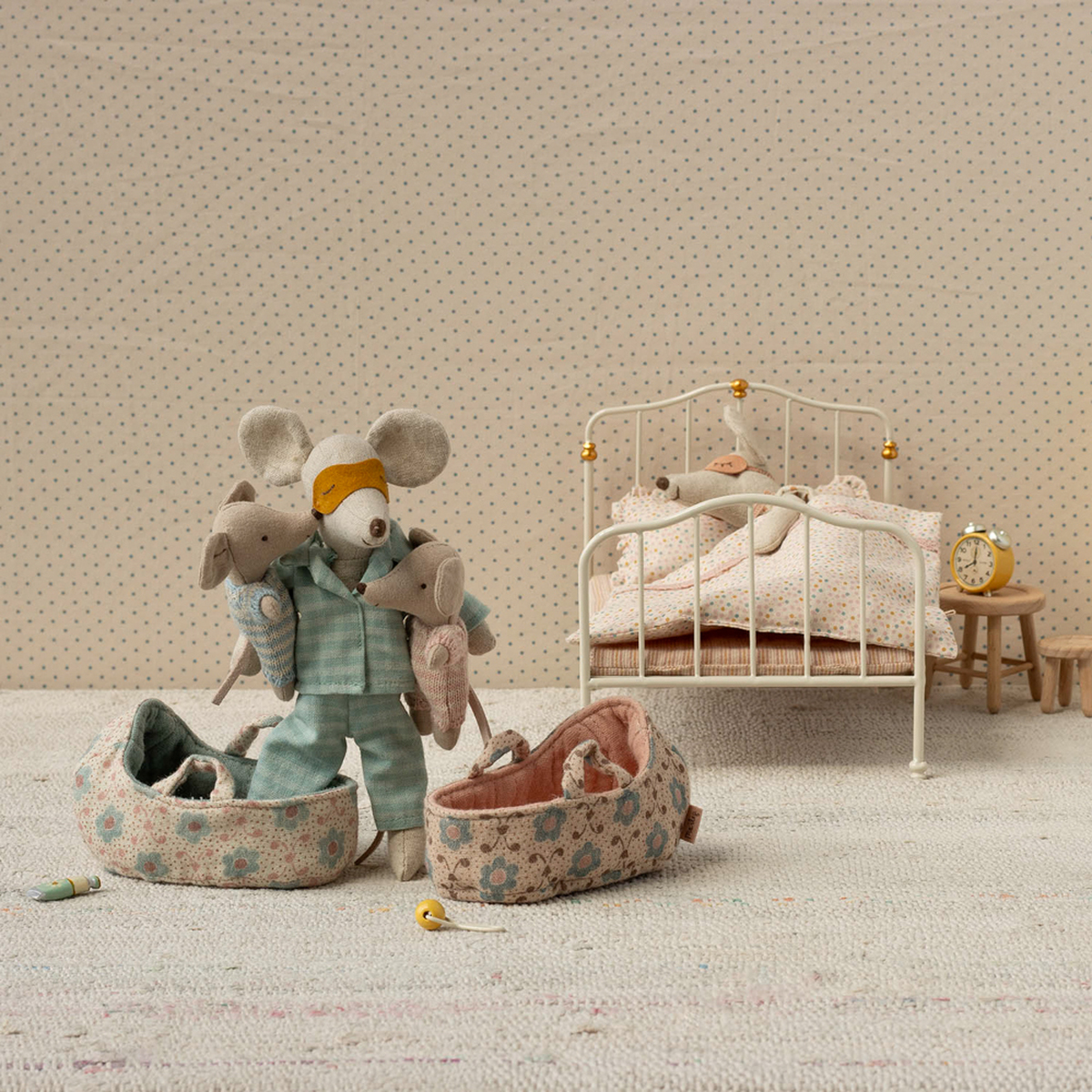 Zwei kleine Stoffmäuse in gemusterten Tragetaschen stehen in einem liebevoll eingerichteten Miniatur-Kinderzimmer mit einem weißen Bett, zarter Bettwäsche, Nachttisch, Wecker und einer kleinen Kommode, geeignet als Spielzeug und Geschenk für Kinder.