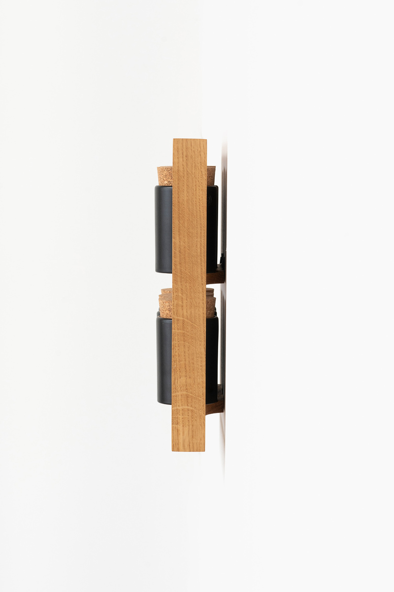 Ein minimalistisches Gewürzregal aus Holz zur Wandmontage mit schwarzen Behältern. Das Regal enthält zwei Schichten für Gewürzgläser. Das Design ist modern und platzsparend.