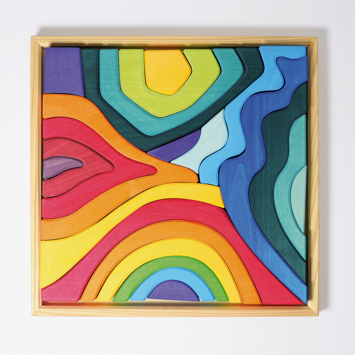Bausatz aus Holz in Form einer abstrakten Landschaft mit verschiedenen geschwungenen Teilen in bunten Farben, eingerahmt von einem Holzrahmen.