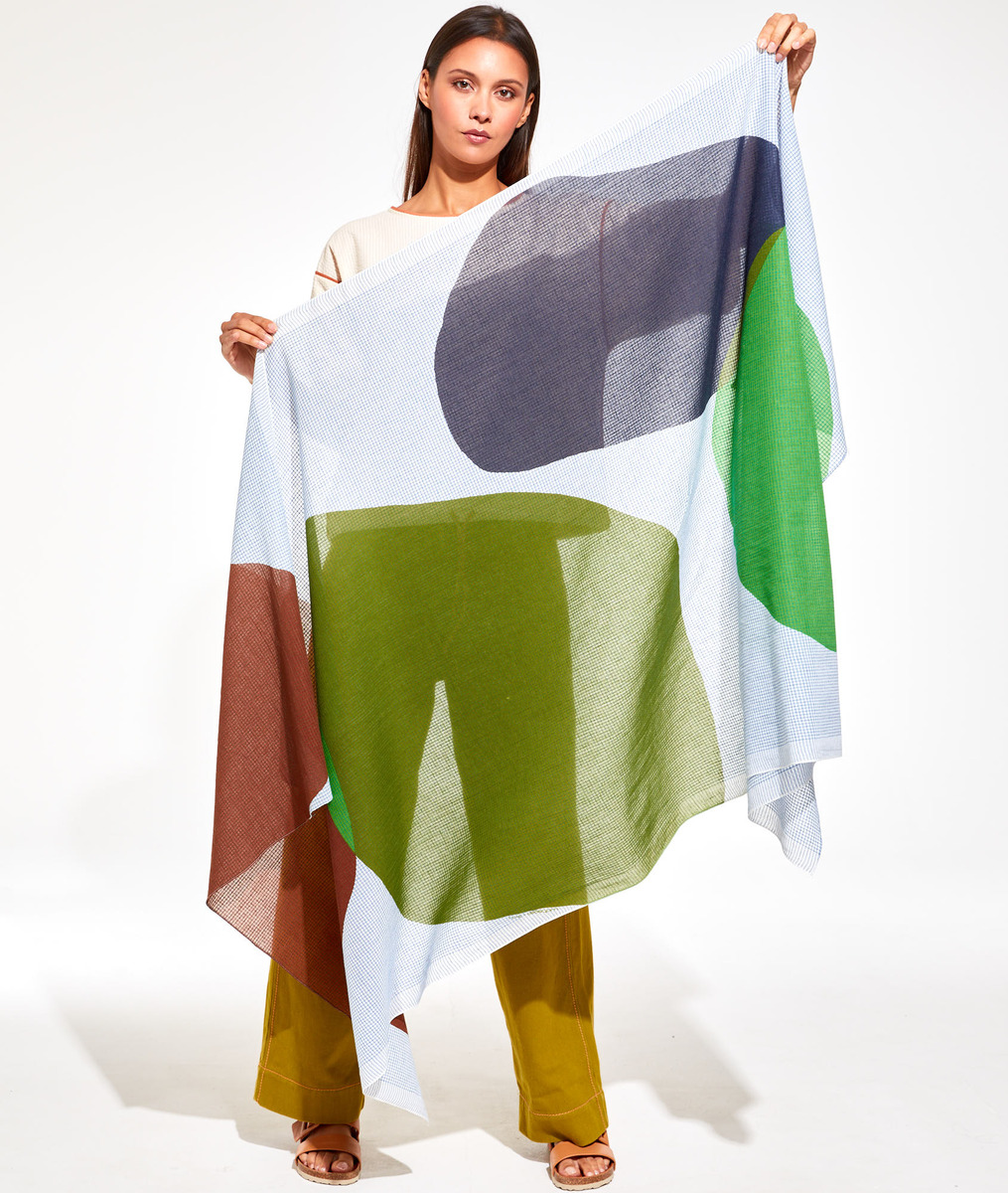 Frau präsentiert leichtes Baumwolltuch 'Galet' mit abstraktem Design in Weiß, Grün, Blau und Braun. Vielseitiges Modeaccessoire für stilvolle Anlässe.