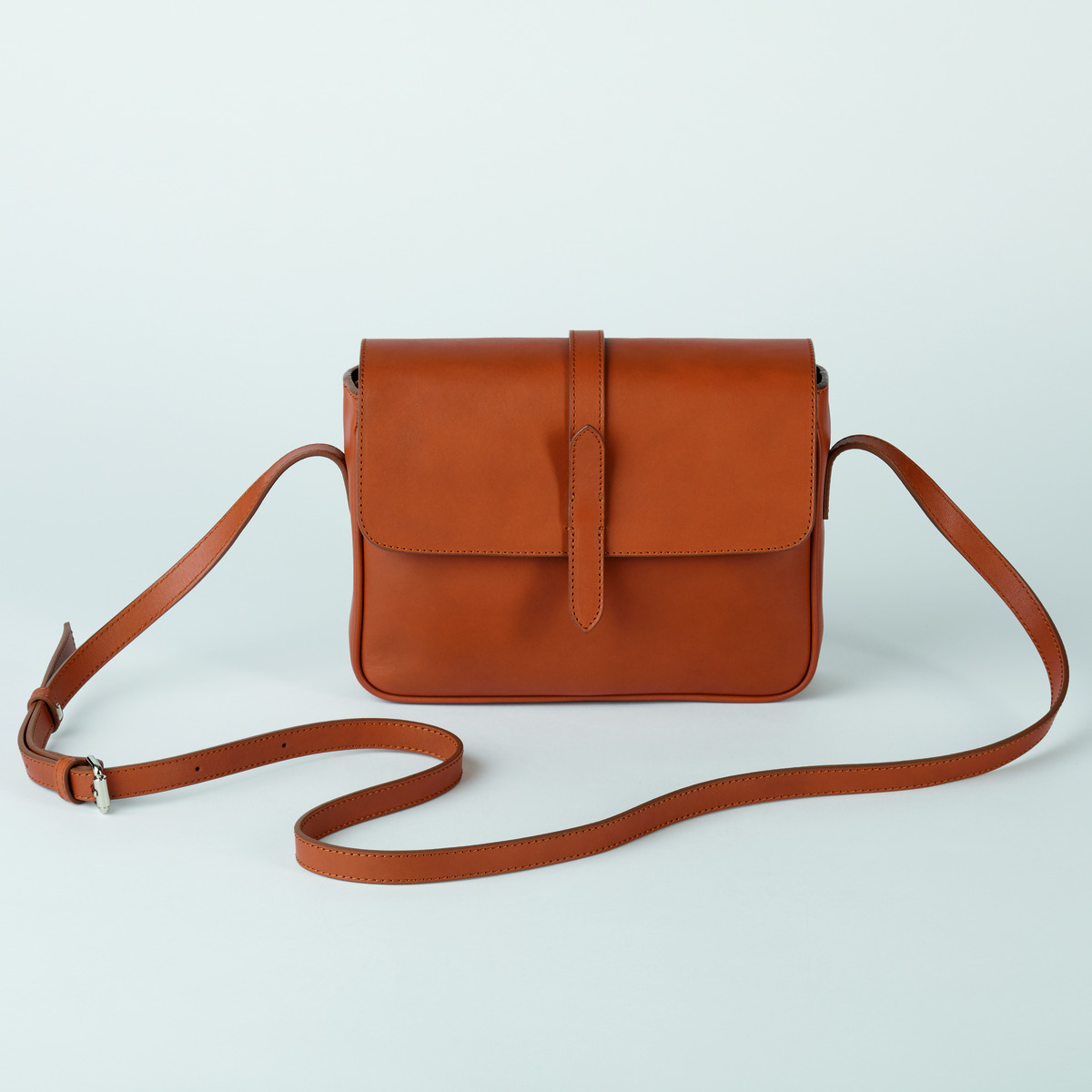 Kleine Satteltasche aus cognacfarbenem Leder mit einem verstellbaren Schulterriemen und einer Schnalle als Verschluss.
