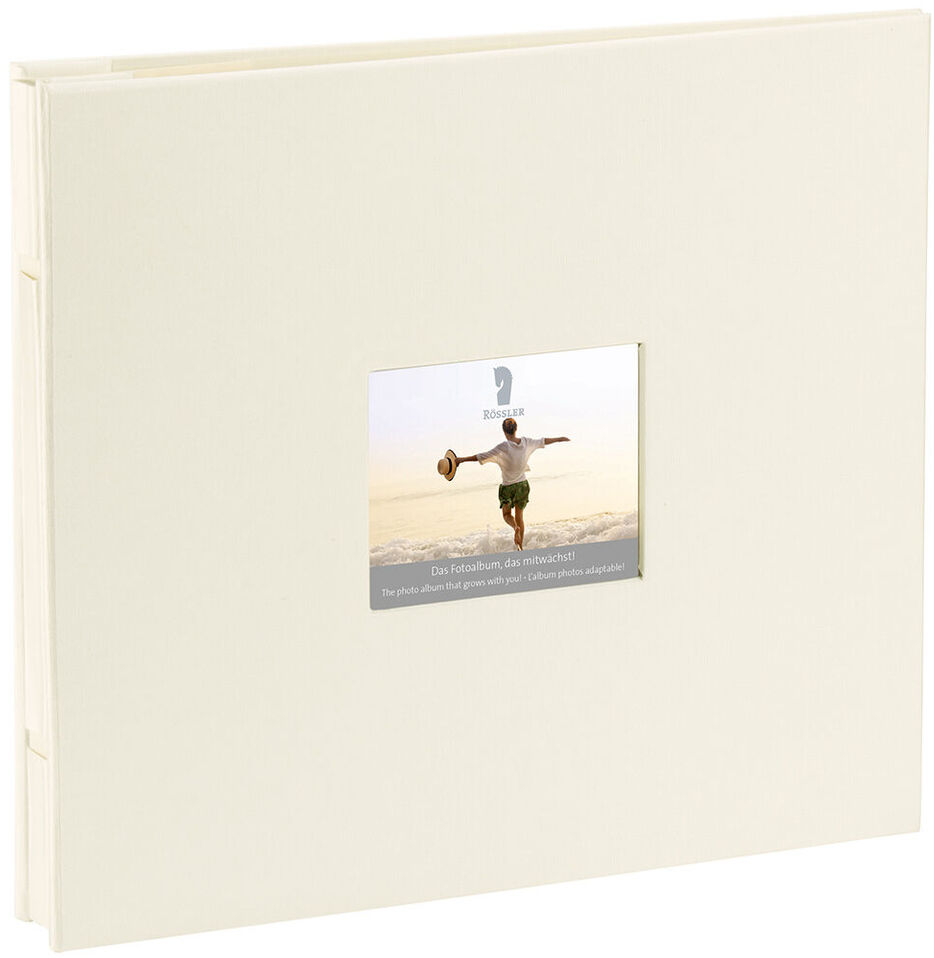 Ein cremefarbenes Fotoalbum mit einem kleinen quadratischen Fenster auf dem Einband. Das Fenster zeigt ein Bild von einer Person, die an einem sonnigen Tag nach oben springt. Das Album ist schlicht und elegant gestaltet.