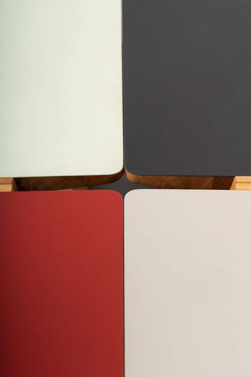 Ein modernes Stehpult namens »buckowski« mit einer minimalistisch gestalteten Oberfläche in Weiß, Rot, Creme und Schwarz, kombiniert mit Holzelementen. Es ist ideal für das Büro oder Home-Office geeignet, um einen ergonomischen und flexiblen Arbeitsplatz zu schaffen.