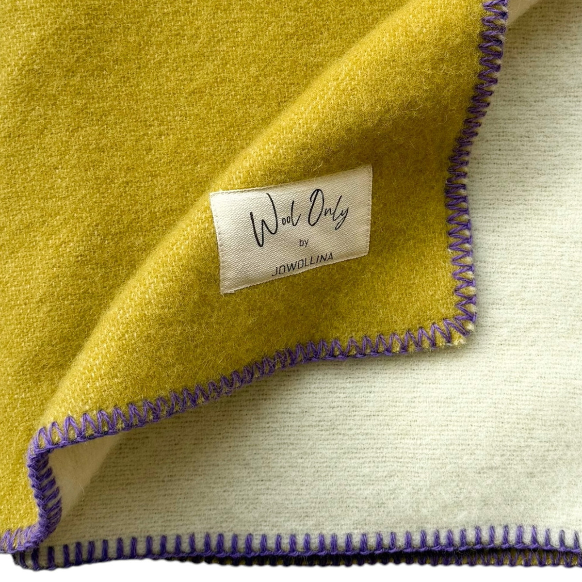 Gelbe und weiße Doubleface-Decke mit lila Randnaht, aus Baumwolle gefertigt. Perfekt für Gemütlichkeit und als Wohnaccessoire geeignet.