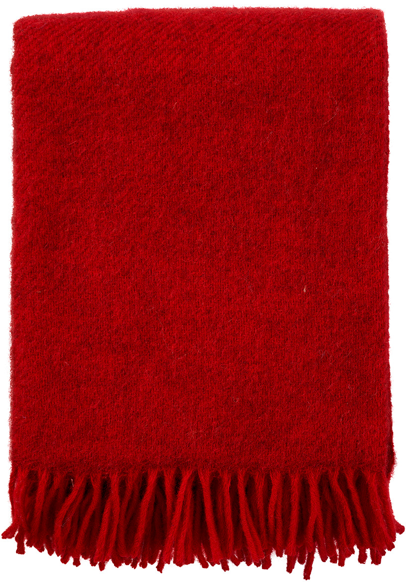 Eine rote Decke mit Fransen, bekannt als »Gotland«. Sie besteht aus weichem Material und eignet sich ideal zum Kuscheln auf dem Sofa oder im Bett.