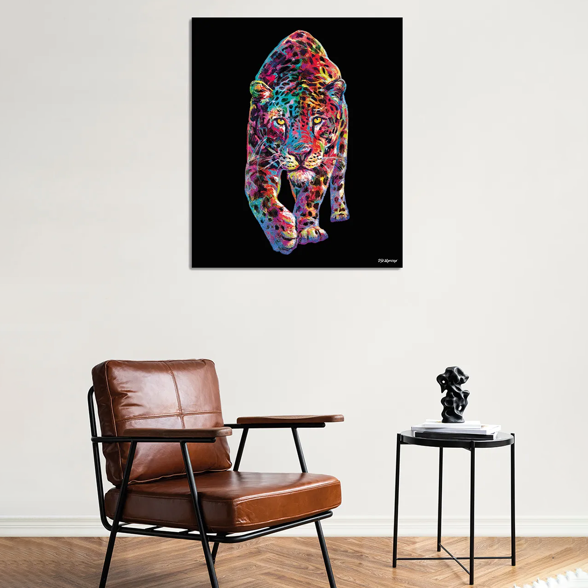 Großformatiger Kunstdruck mit einem farbenfroh gestalteten Leoparden auf schwarzem Hintergrund, gerahmt und hinter Acrylglas. Der Panther ist in lebhaften, kontrastreichen Farben dargestellt. Der Druck hängt über einem modernen Sessel und einem Beistelltisch in einem stilvoll eingerichteten Wohnzimmer.