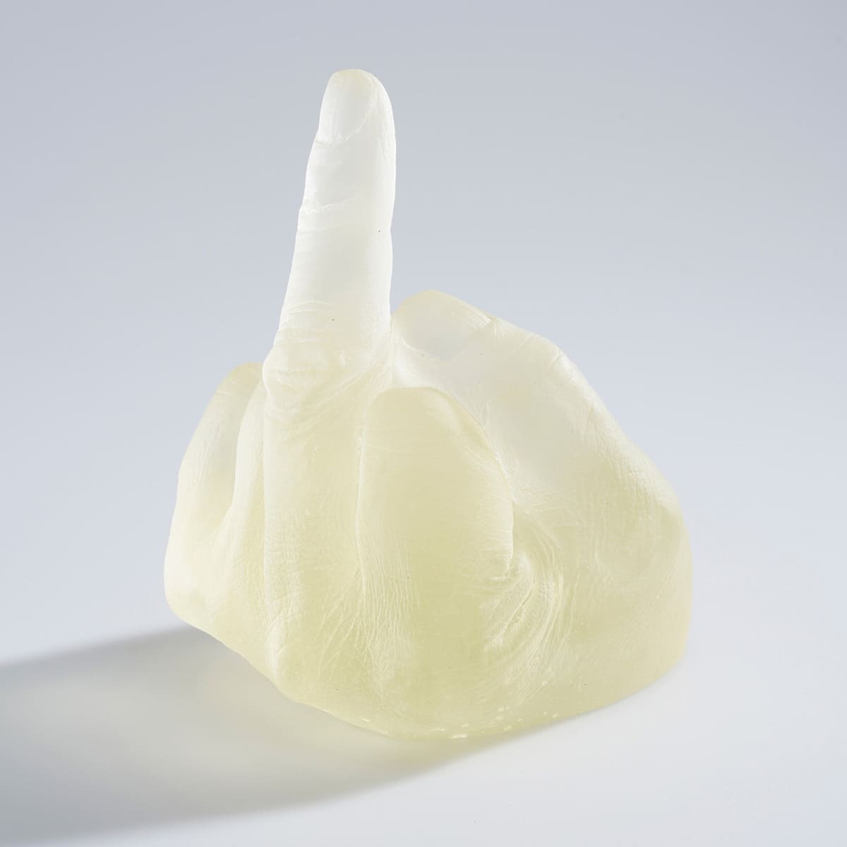 Eine transparente Glasskulptur von Ai Weiwei, welche eine Hand darstellt, die den Mittelfinger zeigt. Das Kunstwerk steht vor einem neutralen Hintergrund.