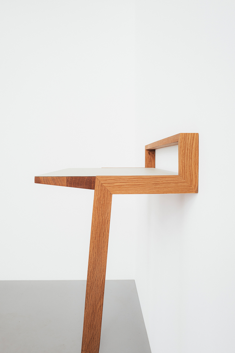 Ein modernes, minimalistisches Stehpult namens »buckowski«, aus Holz gefertigt. Das Pult ist an eine Wand montiert und verfügt über eine schlanke, platzsparende Konstruktion. Ideal für Home Office und kreative Arbeitsplätze.